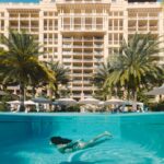 a woman swimming in a pool in front of a hotel